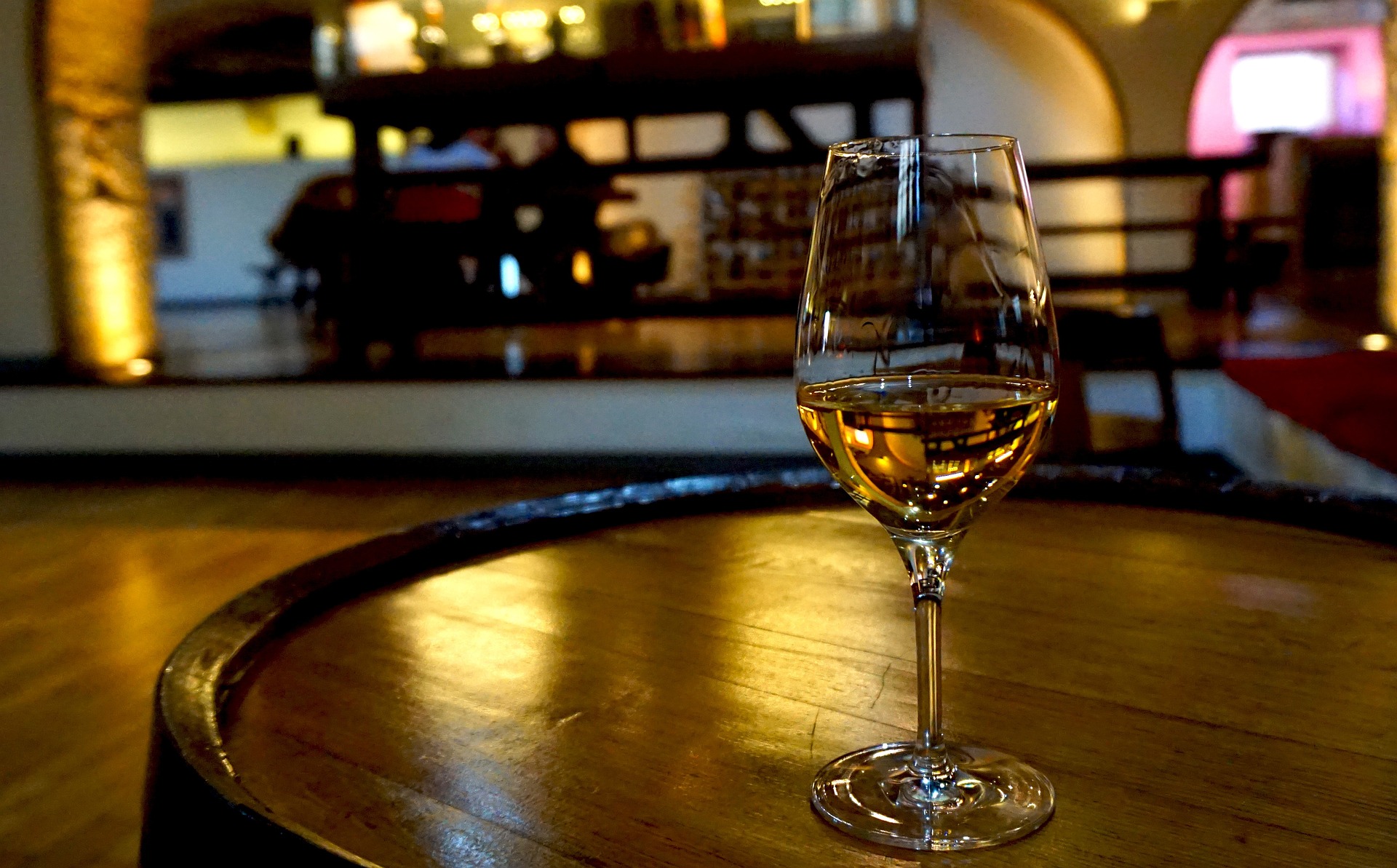 Glass of wine sitting on top of an oak barrel.