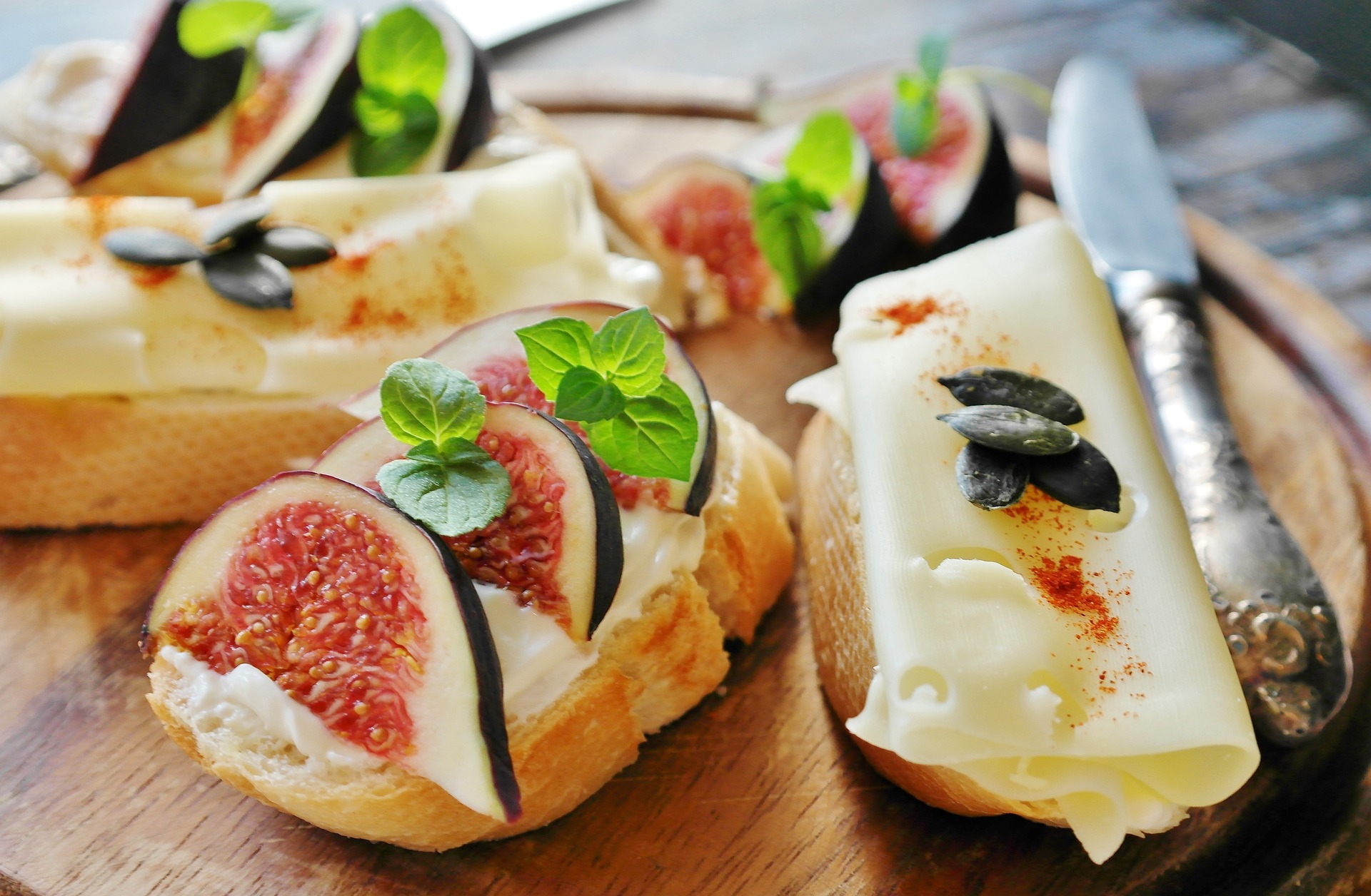 French bread with cheese, fresh figs, and basil on top of a cutting board